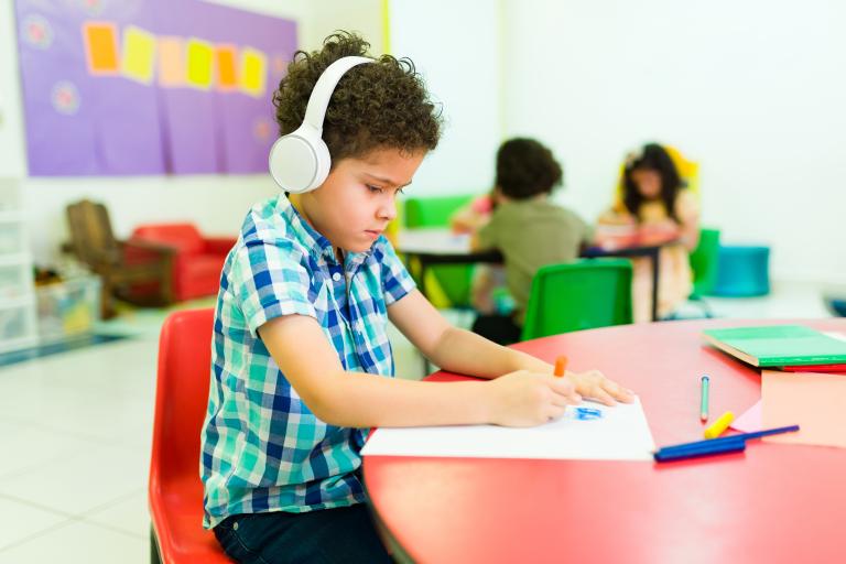 child at school table with headphones
